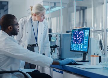 Modern Medical Research Laboratory: Two Scientists Use Computer with Screen Showing DNA Gene Analysis, Specialists Discuss Innovative Technology. Advanced Scientific Lab for Medicine, Biotechnology