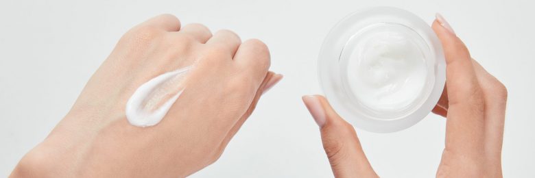 panoramic shot of woman applying cream on skin and holding jar isolated on white panoramic shot of woman applying cream on skin and holding jar isolated on white